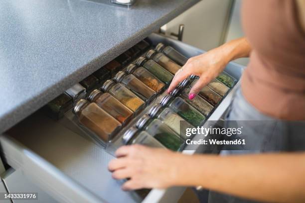 hands of woman arranging spice jars in kitchen drawer - spice fotografías e imágenes de stock