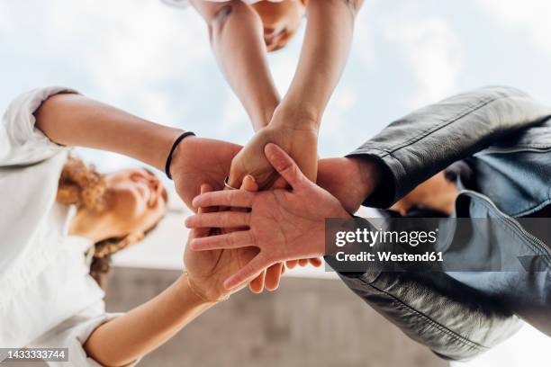 young women stacking hands together - hand stack stock pictures, royalty-free photos & images