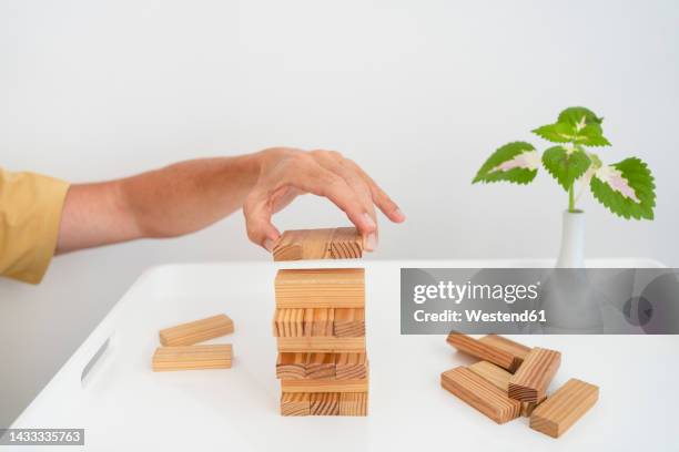 hand of man stacking wooden blocks on coffee table - jenga stockfoto's en -beelden