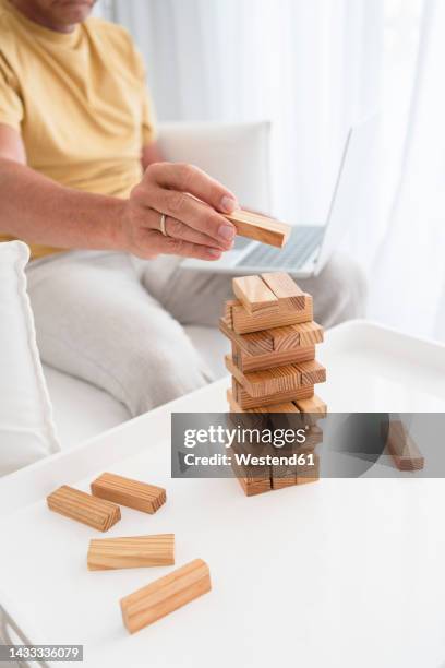 mature man stacking toy blocks on coffee table - block removal game stock pictures, royalty-free photos & images
