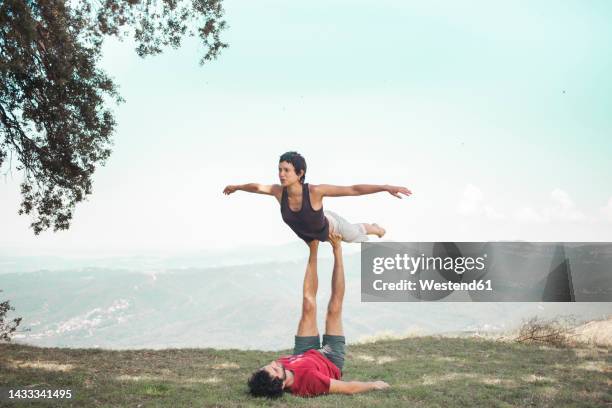couple doing acroyoga in front of sky - 腕を広げる ストックフォトと画像