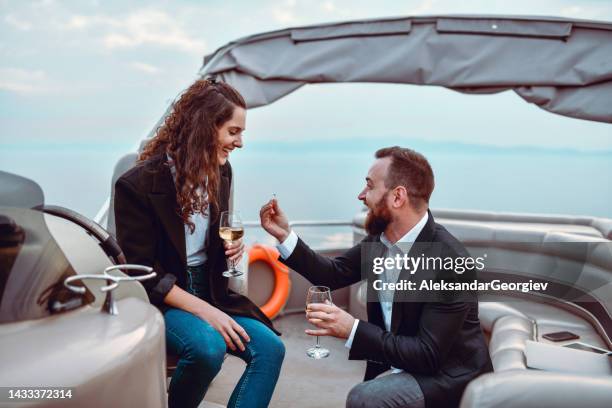 excited male proposing to girlfriend while riding on catamaran - team engagement stock pictures, royalty-free photos & images