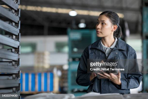 increasing efficiency of supply chain planning in the automotive industry. an asian female engineer holding a tablet computer and standing surround a car chassis on a pallet to manage and control for supply to production line assembly. - base de données photos et images de collection