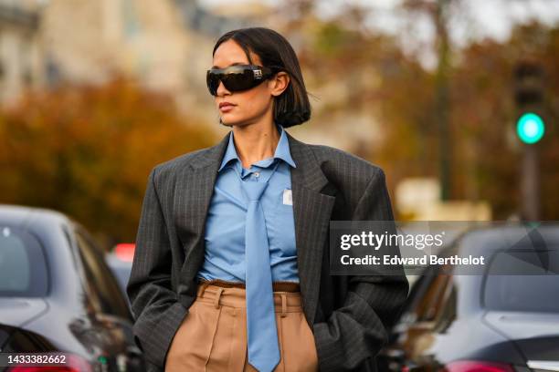 Alexandra Guerain wears black sunglasses from Chanel, a pale blue shirt, a gray checkered print pattern oversized blazer jacket, beige wide legs /...