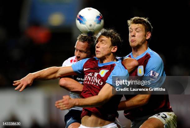 Kevin Davies of Bolton Wanderers goes up for a header with Stephen Warnock and Nathan Baker of Aston Villa the Barclays Premier League match between...