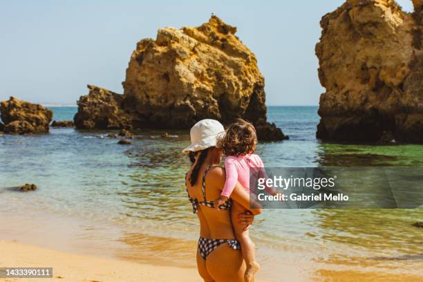 woman bonding with baby girl at the beach - albufeira beach stockfoto's en -beelden