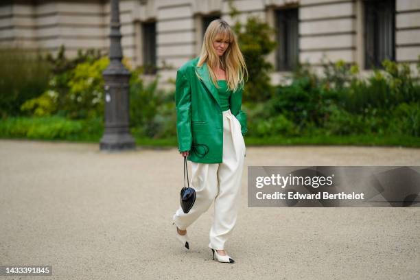 Jeanette Madsen wears a green shiny leather embossed logo shoulder-off top, a matching green shiny leather embossed logo pattern oversized blazer...