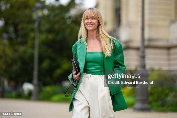 Jeanette Madsen wears a green shiny leather embossed logo shoulder-off top, a matching green shiny leather embossed logo pattern oversized blazer...