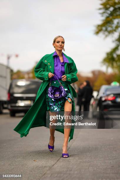 Leonie Hanne wears a gold large logo pendant earring from Fendi, a gold large F earring from Fendi, a purple leopard print pattern silk buttoned...