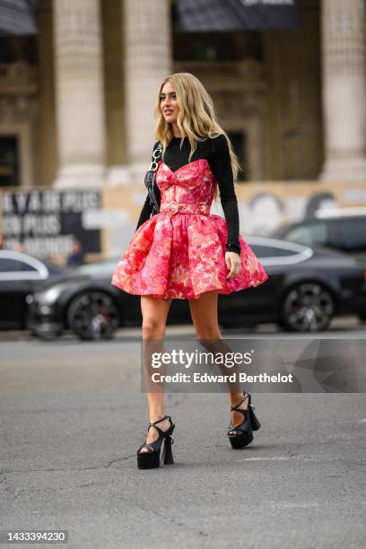 Emili Sindlev wears a black long sleeves t-shirt, a red / orange / pale yellow tie and dye print pattern shoulder-off / puffy short sleeves, a blue...