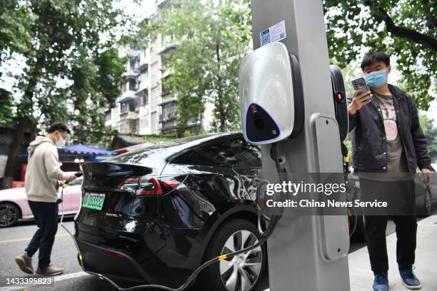 Man charges a Tesla Model Y electric car at a charging point converted from a lamp post on October 14, 2022 in Chengdu, Sichuan Province of China.