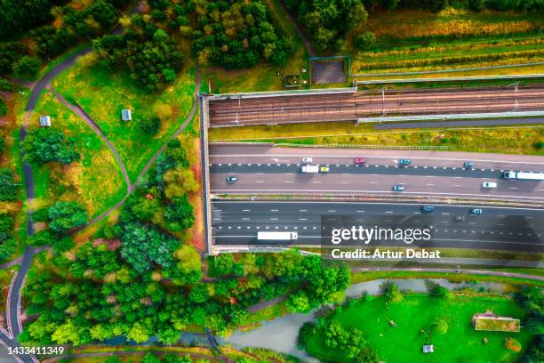 directly above drone view of semi underground highway crossing under green tunnel with public park in the netherlands. - organisation environnement stock-fotos und bilder