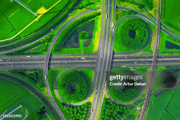 aerial view of a highway intersection with junctions and vivid green sustainable landscape in the netherlands. - air freight transportation stock pictures, royalty-free photos & images