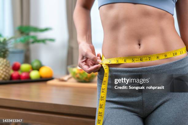 slim woman measuring waist with vegetable and fruit background, healthy care concept. - slim skinny stockfoto's en -beelden