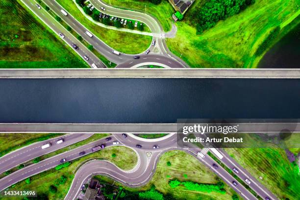 aerial view of the sart canal bridge crossing above traffic circle in the green landscape of belgium. - belgium canal stockfoto's en -beelden