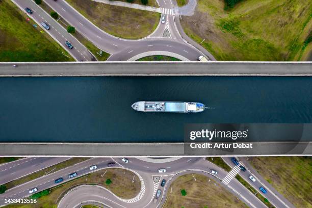 aerial view of a tour ship sailing the sart canal bridge crossing road in belgium. - kanal stock-fotos und bilder
