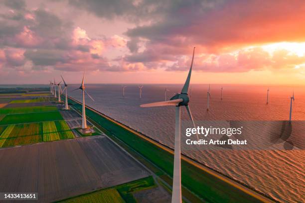 aerial view of offshore wind park with patchwork landscape in the netherlands with dramatic sunset. - molino de viento fotografías e imágenes de stock