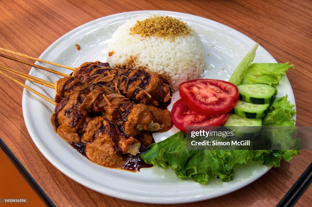 Plate of chicken skewers with satay sauce (sate ayam) on a restaurant table