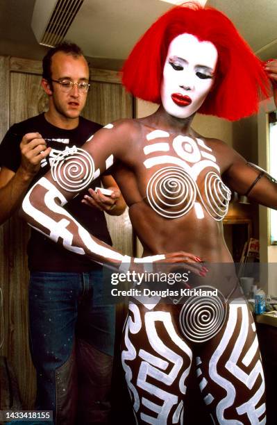 American artist Keith Haring applies body paint to Jamaican-American model, musician, and actress Grace Jones during the filming of 'Vamp' ,...