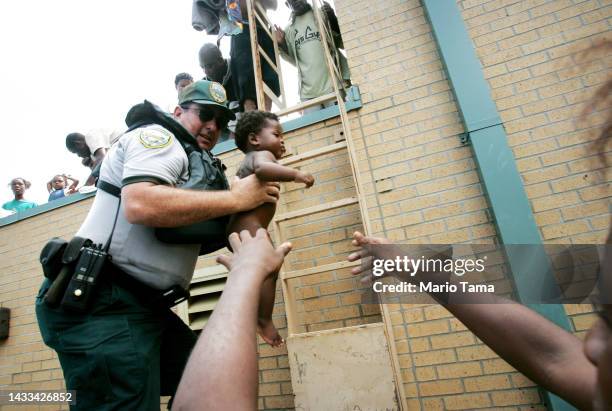Mark Benton, of Louisiana Department of Wildlife and Fisheries, helps to rescue three month old Ishmael Sullivan from a school rooftop after he and...
