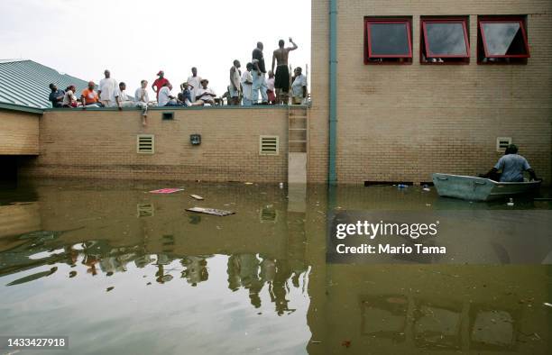 People rest on a school rooftop after being trapped there in high water after Hurricane Katrina August 30, 2005 in New Orleans, Louisiana. Katrina...