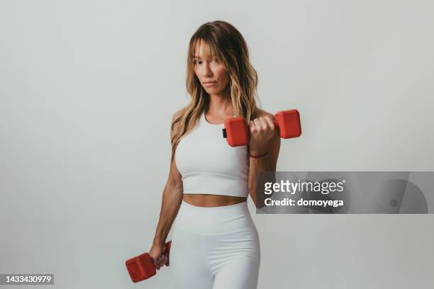 young woman exercising with red color dumbbells - womens hand weights stock pictures, royalty-free photos & images
