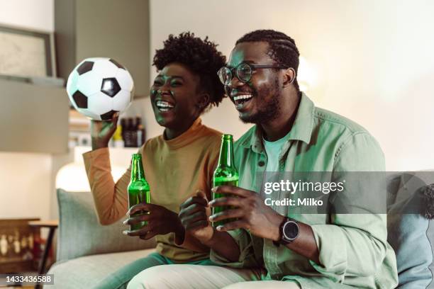 young african-american couple watching sports at home - glee tv program stockfoto's en -beelden
