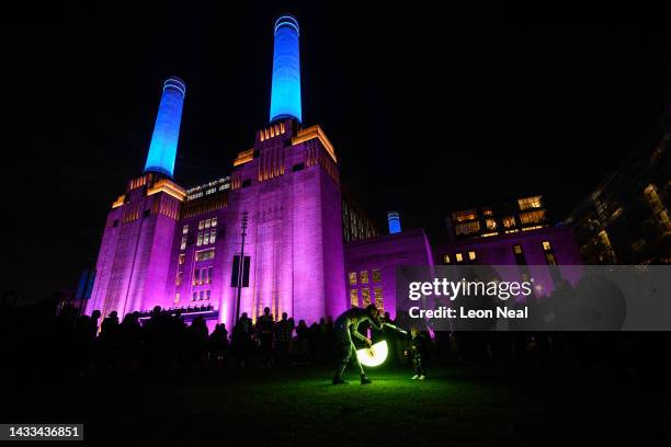 Dancer illuminates a child with light panels during the "Festival of Power" to mark the opening of Battersea Power station on October 14, 2022 in...