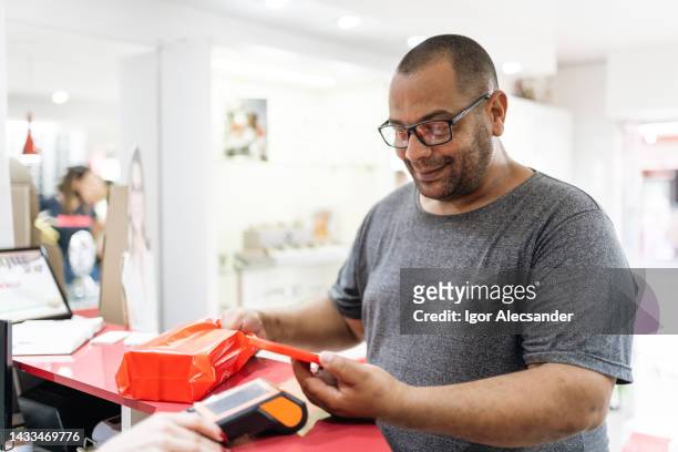 customer at counter paying contactless with smartphone - chubby man shopping stock pictures, royalty-free photos & images