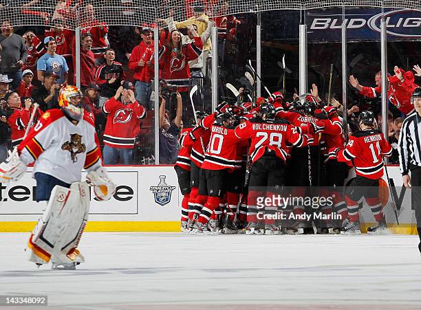 Scott Clemmensen of the Florida Panthers skates away dejected as Travis Zajac of the New Jersey Devils is congratulated by his teammates after...