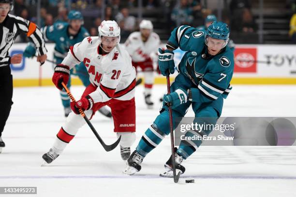 Nico Sturm of the San Jose Sharks controls the puck in front of Sebastian Aho of the Carolina Hurricanes in the first period at SAP Center on October...