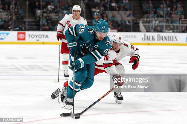 Logan Couture of the San Jose Sharks skates past Sebastian Aho of the Carolina Hurricanes in the second period at SAP Center on October 14, 2022 in...