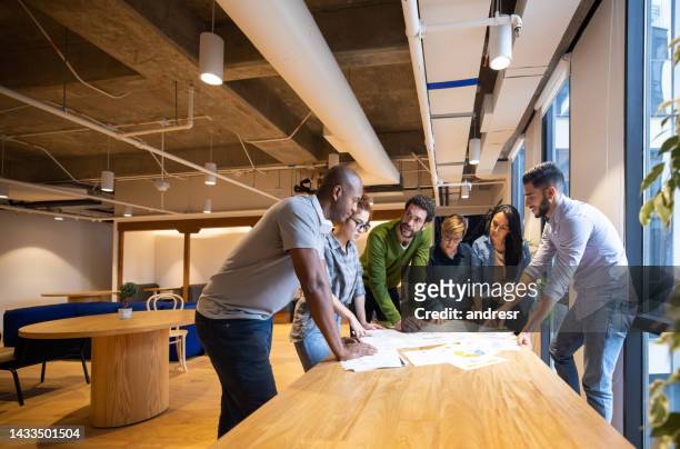 grupo de compañeros de trabajo compartiendo ideas en una reunión de negocios - director creativo fotografías e imágenes de stock