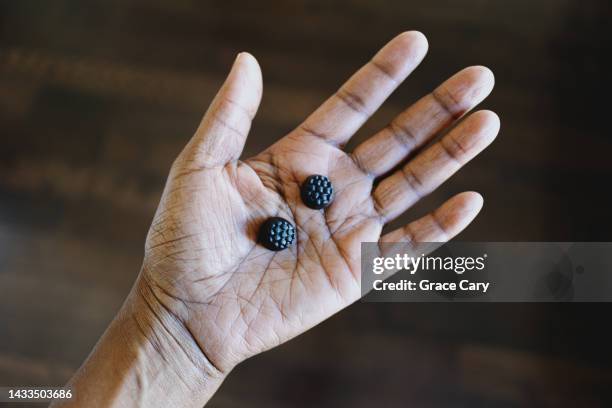 woman holds gummy nutritional supplements in palm of her hand - melatonin stock pictures, royalty-free photos & images