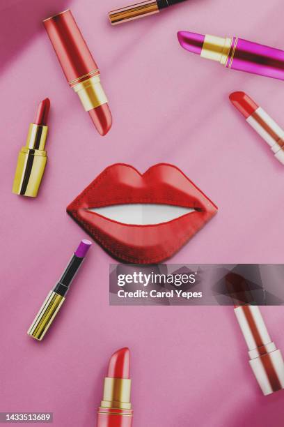 conceptual image of red lips and variety of lipsticks in pink surface. - lip balm stock-fotos und bilder