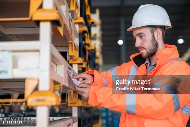 quality control and assurance in an automobile industry supply chain. a male loading worker checks the labeling on the package on pallets and validates the order before supply to the customers. - labeling data stock pictures, royalty-free photos & images