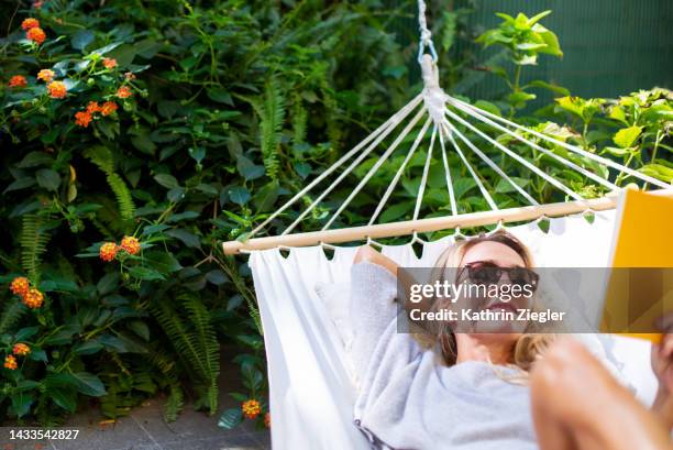 woman relaxing in hammock, reading a book - sunny backyard stock pictures, royalty-free photos & images