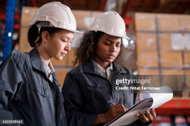 inventory lot tracking to eliminate human error in warehouse operations. a female warehouse supervisor has a discussion with warehouse staff over a lot control checklist to verify in case of a product recall in a distribution warehouse. - produktrückruf stock-fotos und bilder