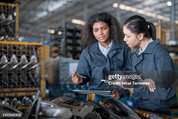 manage lots control of identical products in inventory management. a female warehouse supervisor has a discussion with warehouse staff over a lot control checklist to verify in case of a product recall in a factory warehouse. - product terugroepen stockfoto's en -beelden