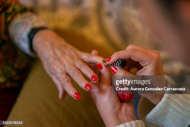 nail polish on the hands of a girl doing the act of painting the nails of an adult hand. - glamourous granny stock pictures, royalty-free photos & images