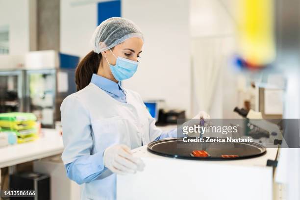 young woman in a laboratory for medicine ,holding test tube using centrifuge - prateleira de tubos de ensaio imagens e fotografias de stock