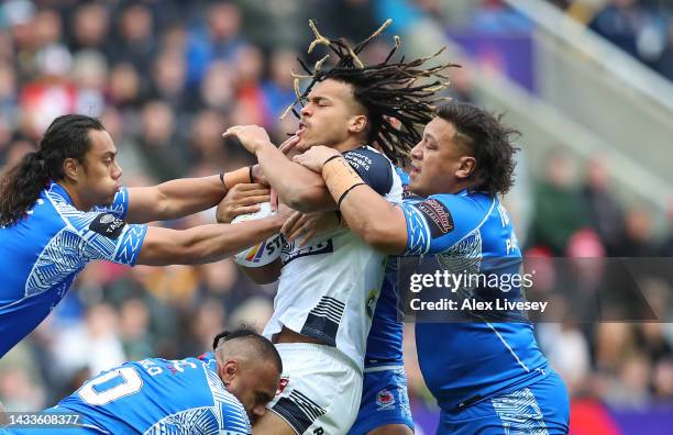 Dom Young of England is tackled by Jarome Luai, Junior Paulo and Josh Papalii of Samoa during the Rugby League World Cup 2021 Pool A match between...