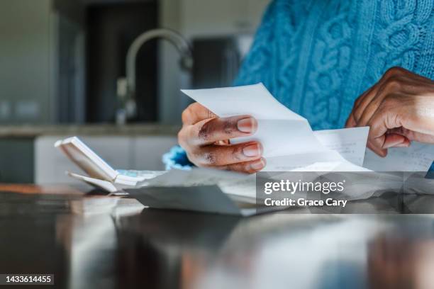 woman reviews receipts at kitchen table - debiteuren stockfoto's en -beelden