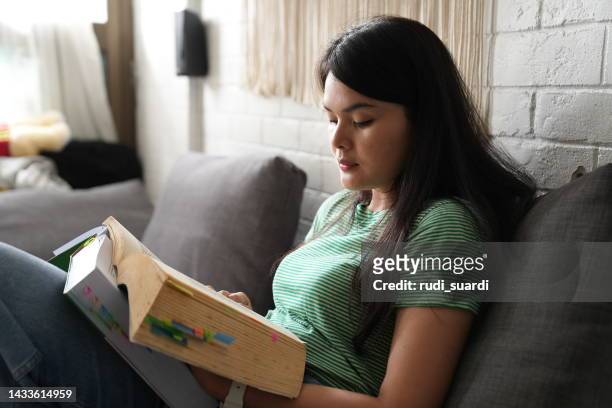 giovane adulto asiatico che legge un libro a casa - chinese dictionary foto e immagini stock
