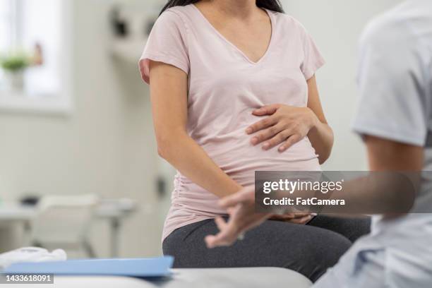 woman at a prenatal medical appointment - pregnant belly stock pictures, royalty-free photos & images