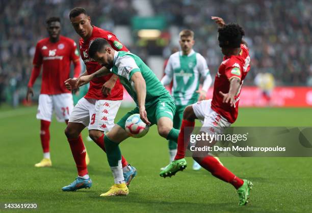 Leandro Barreiro and Karim Onisiwo of 1.FSV Mainz 05 battle for possession with Anthony Jung of SV Werder Bremen during the Bundesliga match between...