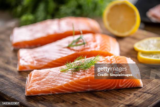 raw salmon fillets onwooden cutting board with dill, rosemary and lemon. - seafood stock pictures, royalty-free photos & images