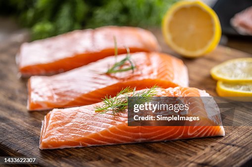 Raw salmon fillets onwooden cutting board with dill, rosemary and lemon. Raw salmon fillets onwooden cutting board with dill, rosemary and lemon.