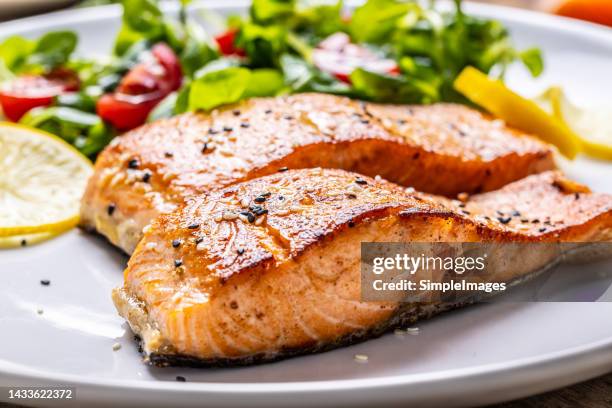 two salmon fillets baked until crispy with sesame, as a side salad marinated with tomatoes. - filet mignon stock pictures, royalty-free photos & images