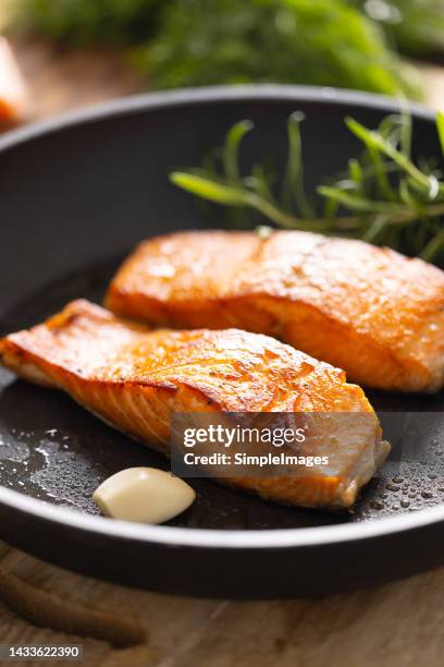 salmon fillets and herbs in an black frying pan. - salmon steak stockfoto's en -beelden